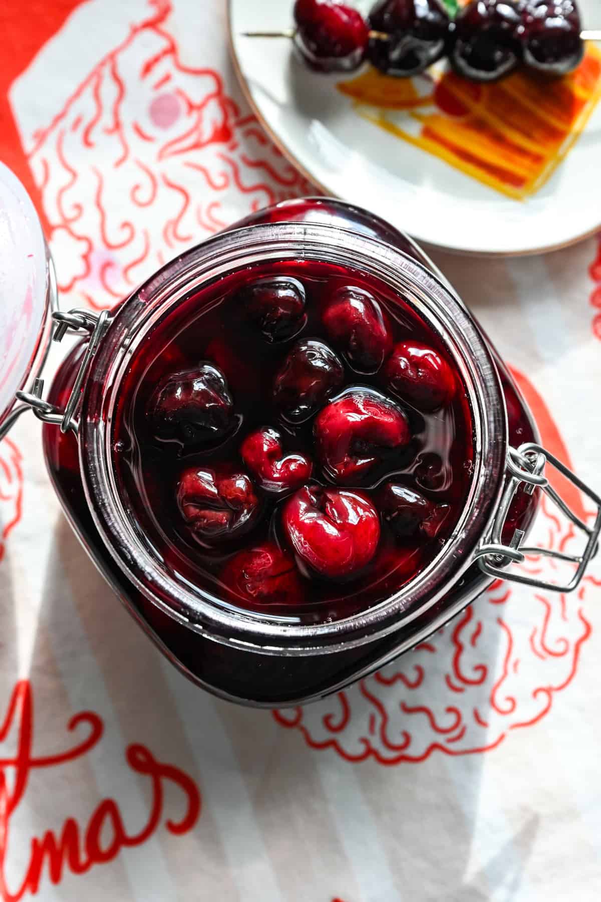 Close up view of cocktail cherries in a glass jar.