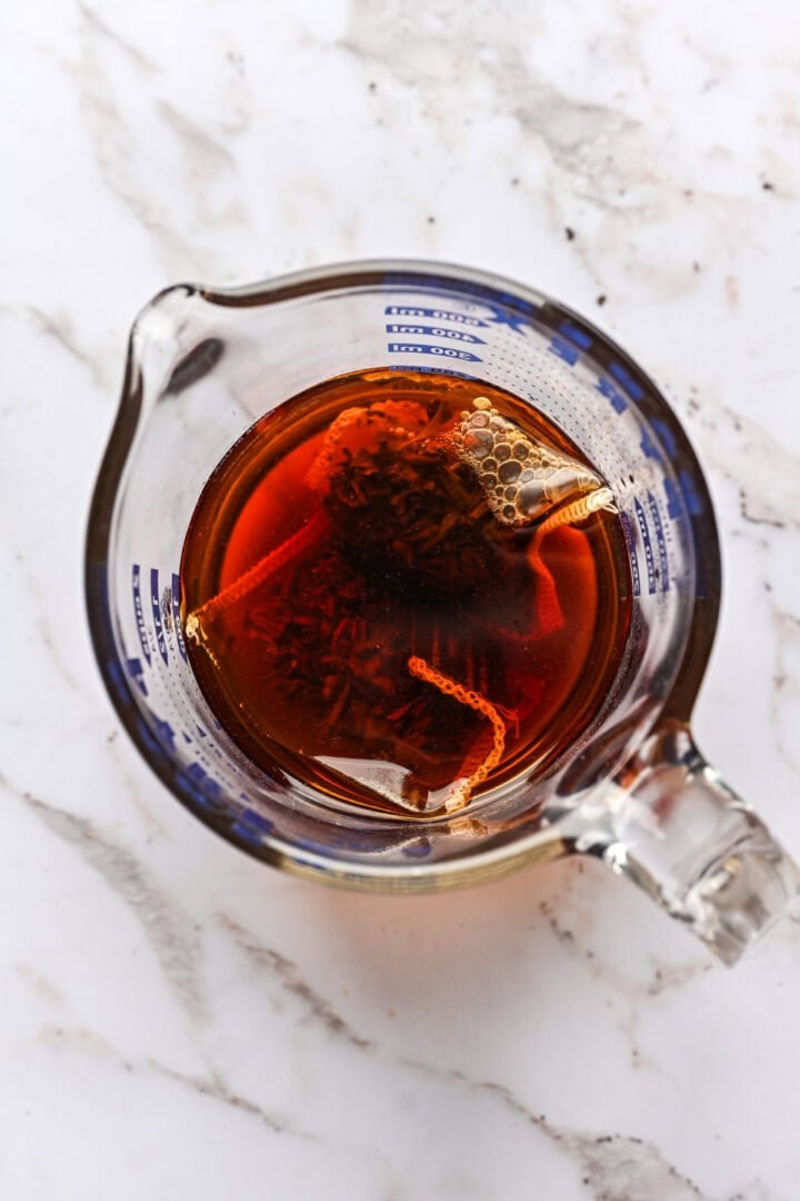 overhead view of earl grey tea steeping in a measuring cup.