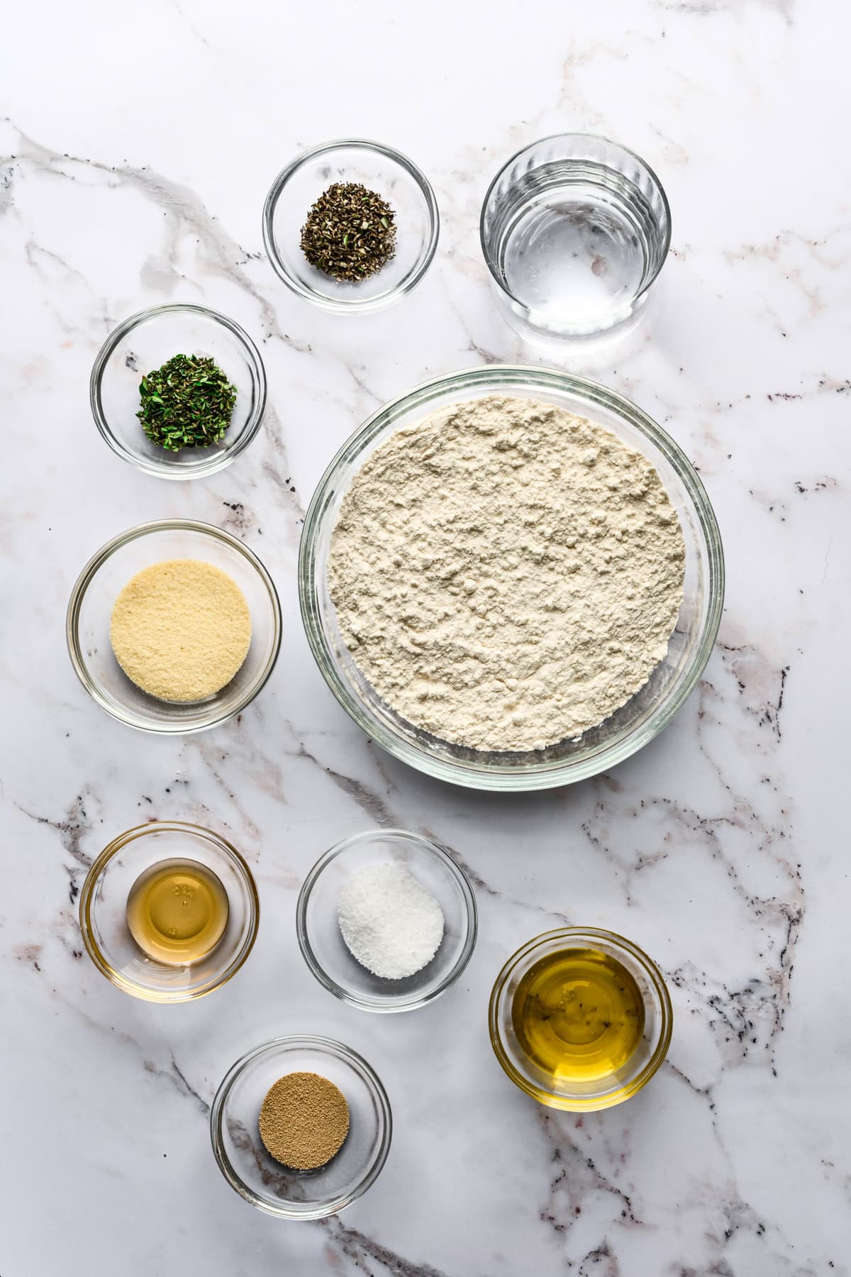 Overhead view of grissini ingredients, including flour and herbs.