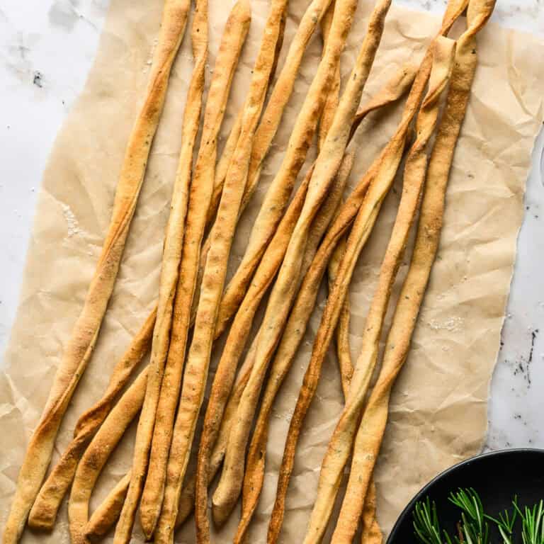 Overhead view of breadsticks on parchment.