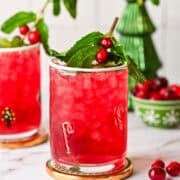 Side view of mistletoe mojito cocktail with mint and cranberry garnish.