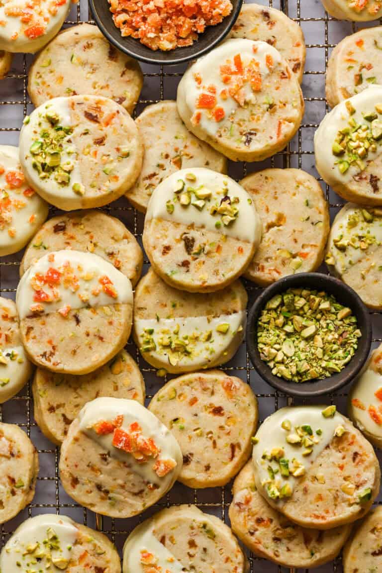 Overhead view of panettone cookies dipped in white chocolate and topped with pistachios and candied oranges.