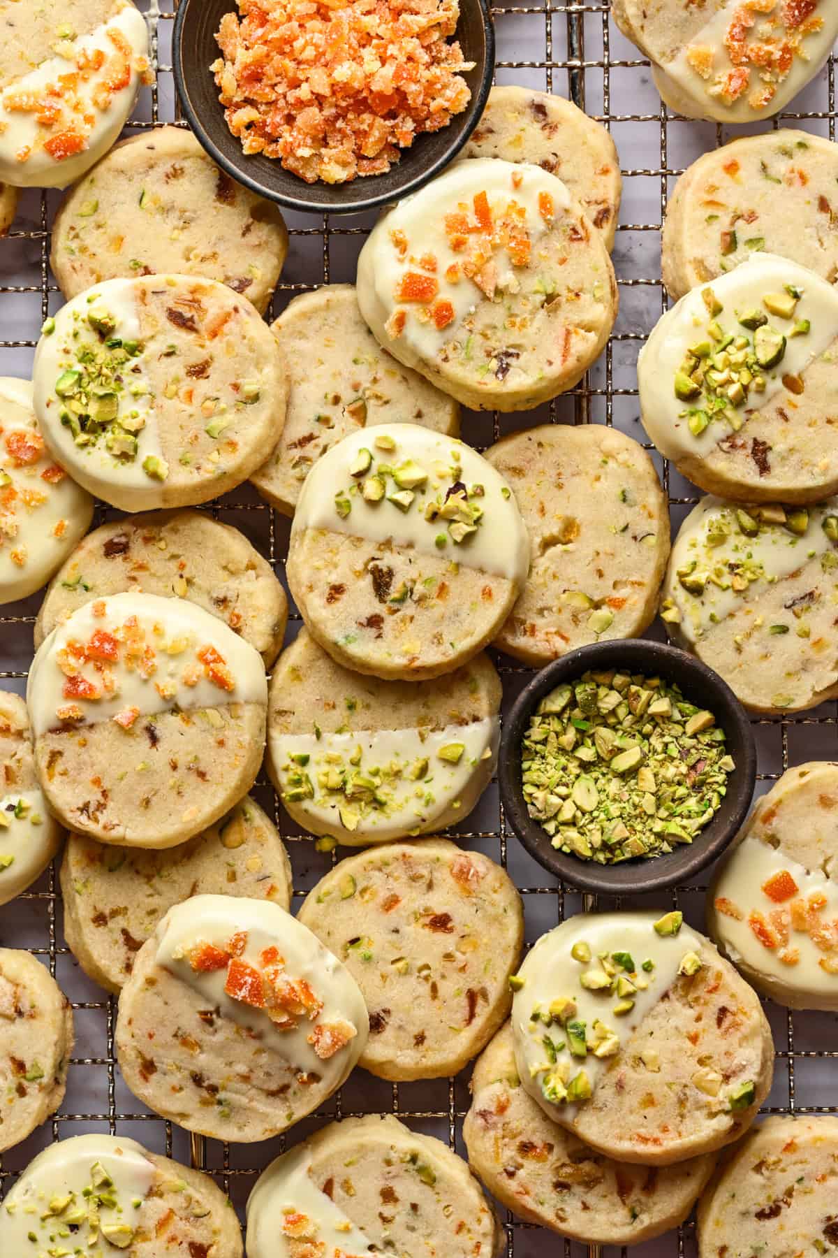 Overhead view of panettone cookies dipped in white chocolate and topped with pistachios and candied oranges.