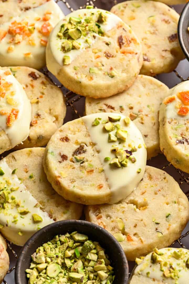 close up view of panettone cookies dipped in white chocolate and topped with pistachios and candied oranges.