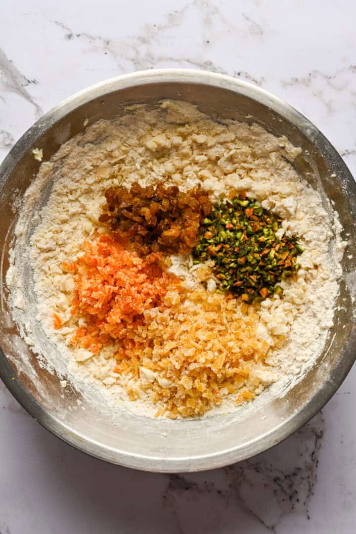 panettone cookie dough in a bowl with chopped pistachios, candied orange and lemon and raisins.