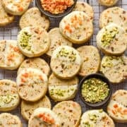 Overhead view of panettone cookies dipped in white chocolate and topped with pistachios and candied oranges.
