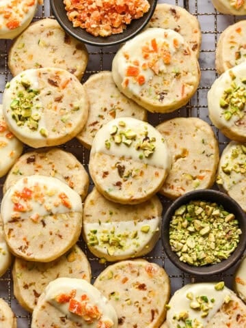 Overhead view of panettone cookies dipped in white chocolate and topped with pistachios and candied oranges.