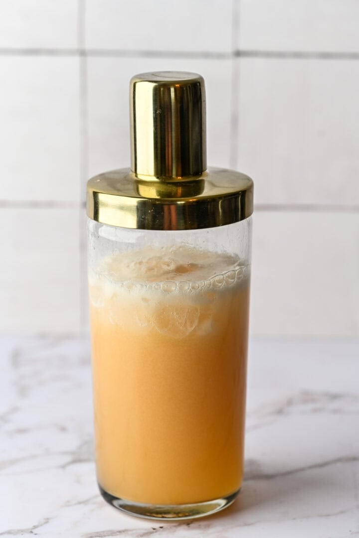 Ingredients for partridge in a pear tree cocktail in cocktail shaker with ice.