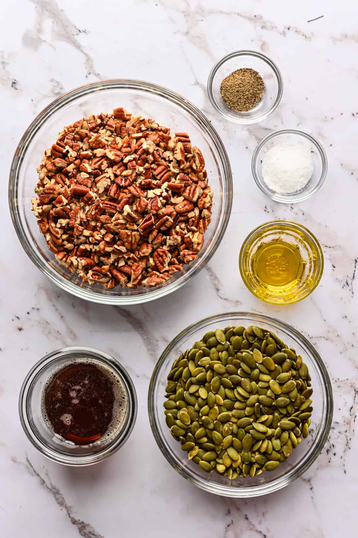 overhead view of ingredients for pecan pepita brittle in small bowls.
