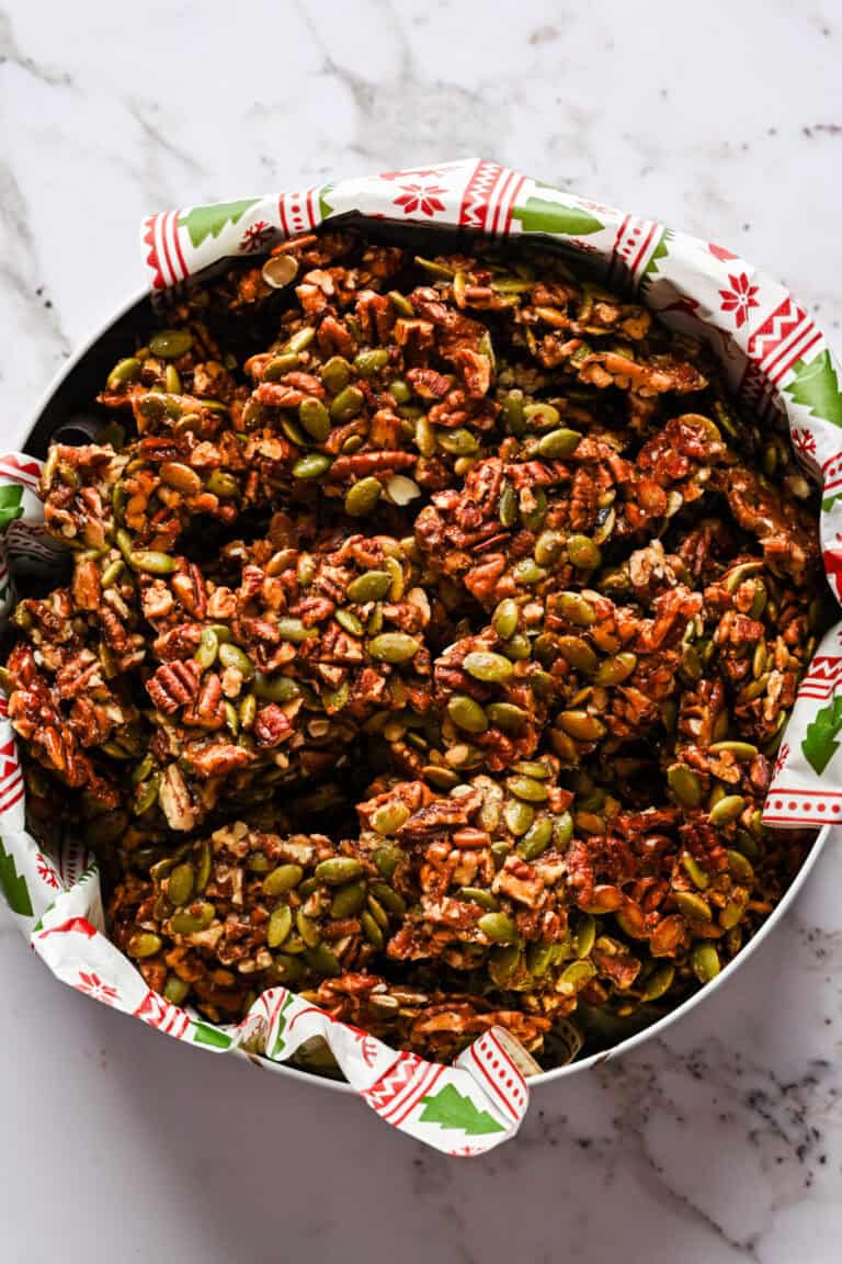 Pecan pepita brittle pieces in a christmas gift tin.