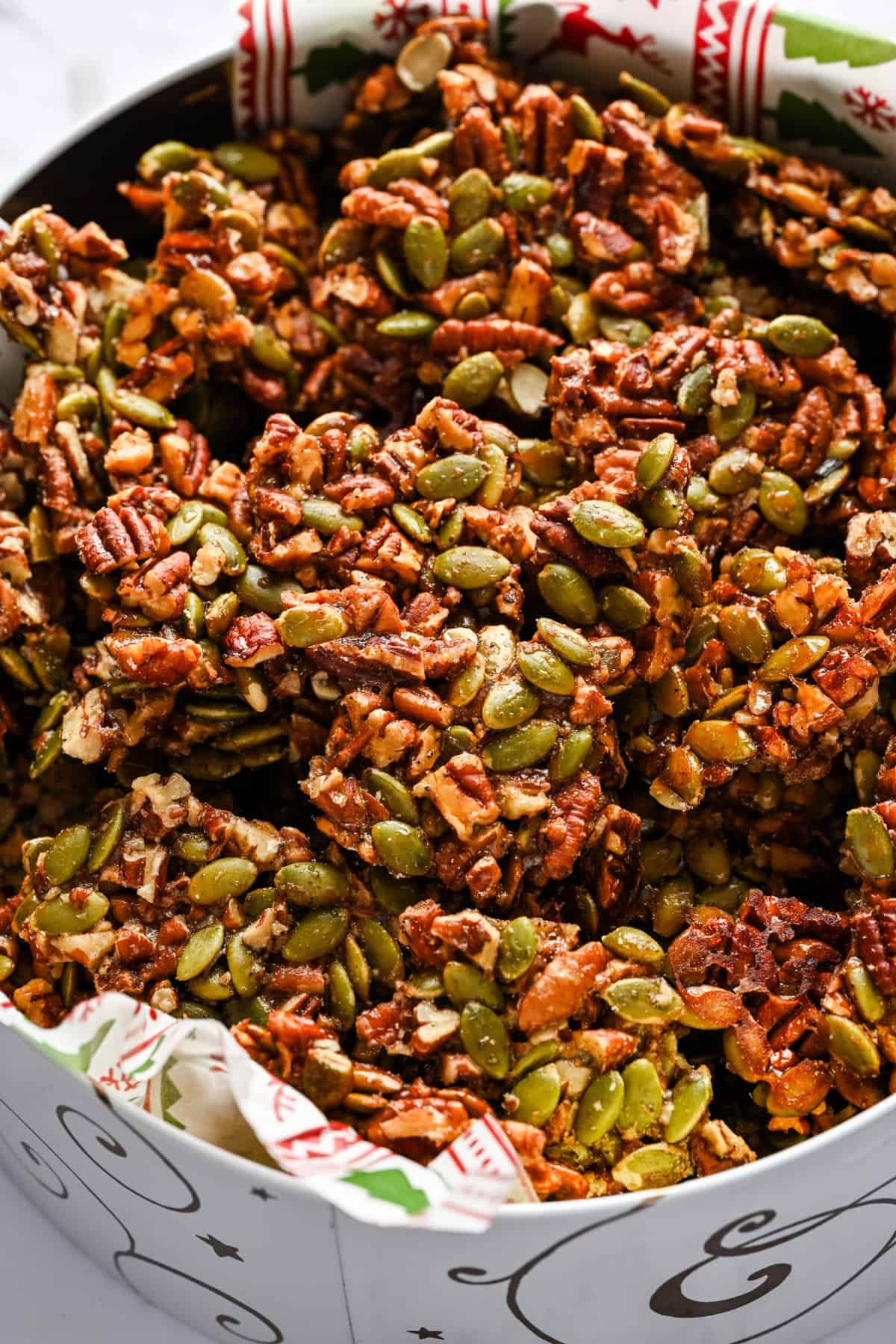 Pecan pepita brittle pieces in a christmas gift tin.