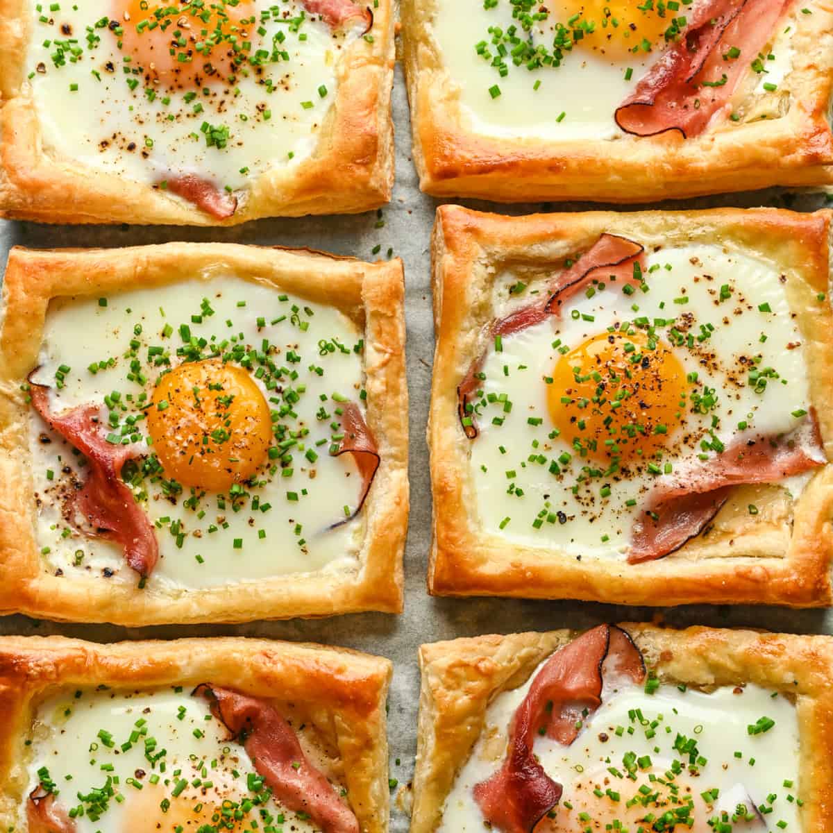 Overhead view of several croque madame on a sheet pan.