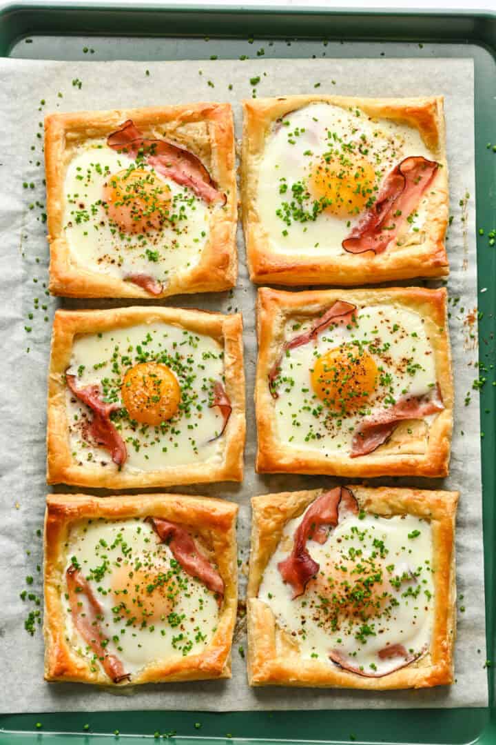 Overhead view of several croque madame on a sheet pan.