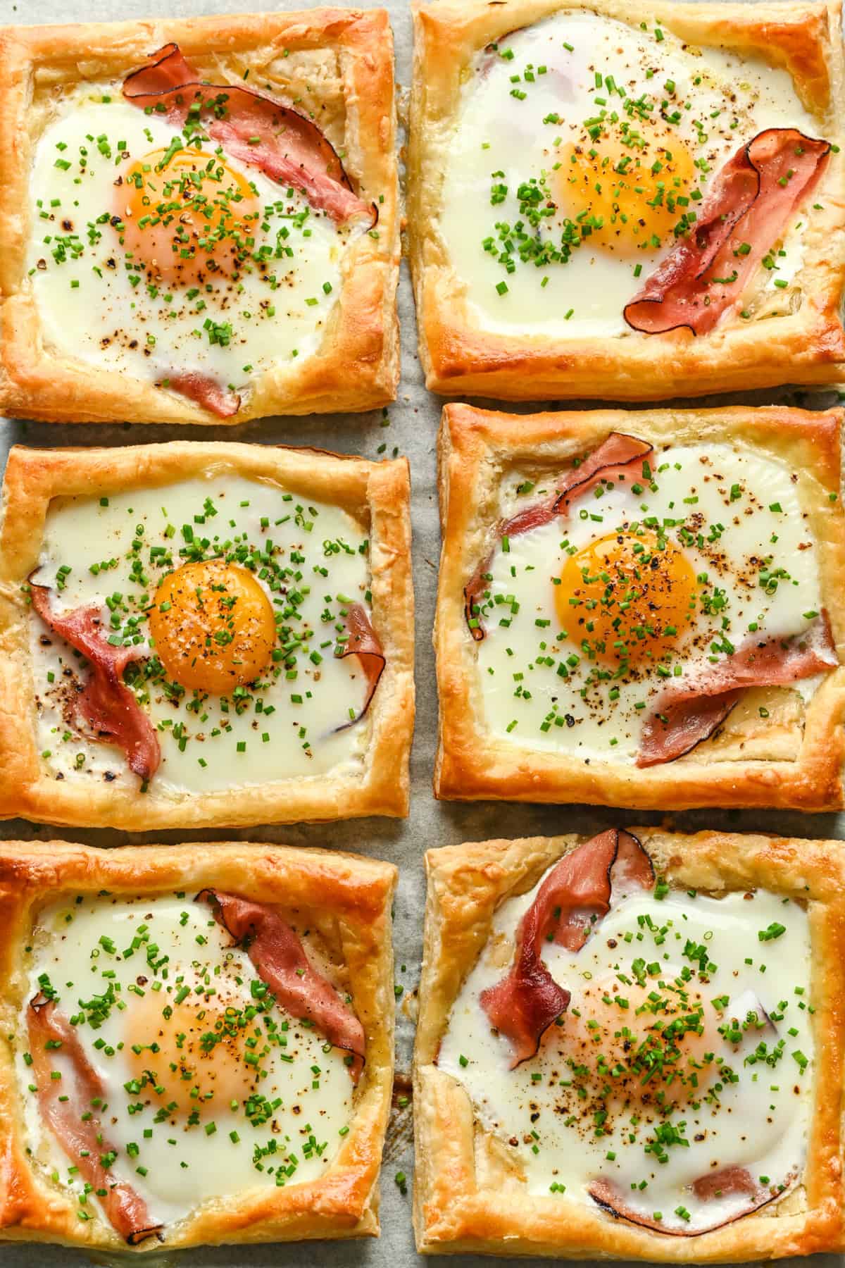 Overhead view of several croque madame on a sheet pan.