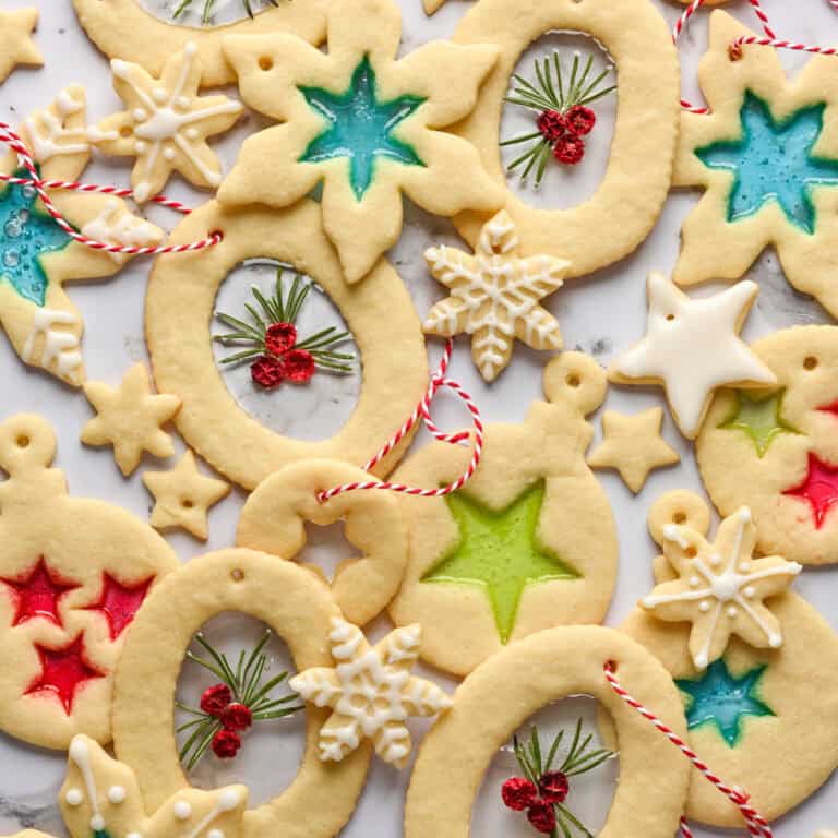 Overhead view of stained glass cookie ornaments on white backdrop.