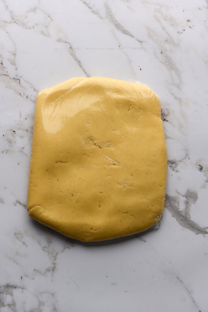 Sugar cookie dough in a rectangle wrapped in plastic wrap.
