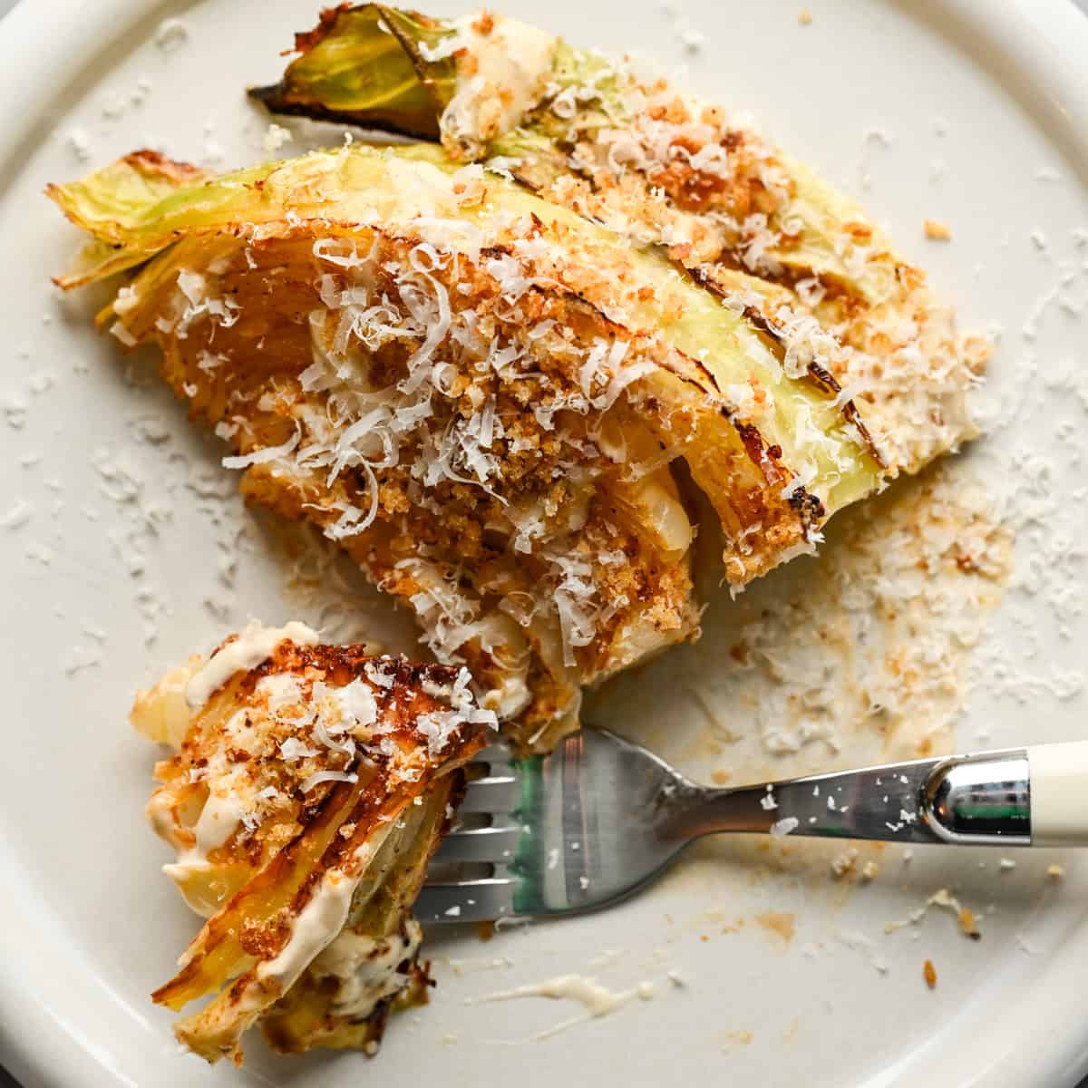 Overhead view of cabbage wedge with caesar dressing and parmesan.