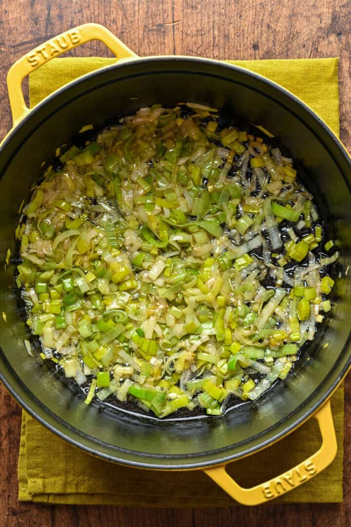 Overhead view of leeks sauteing in a pot.