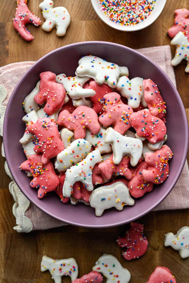 Overhead view of frosted animal cookies in a purple bowl.