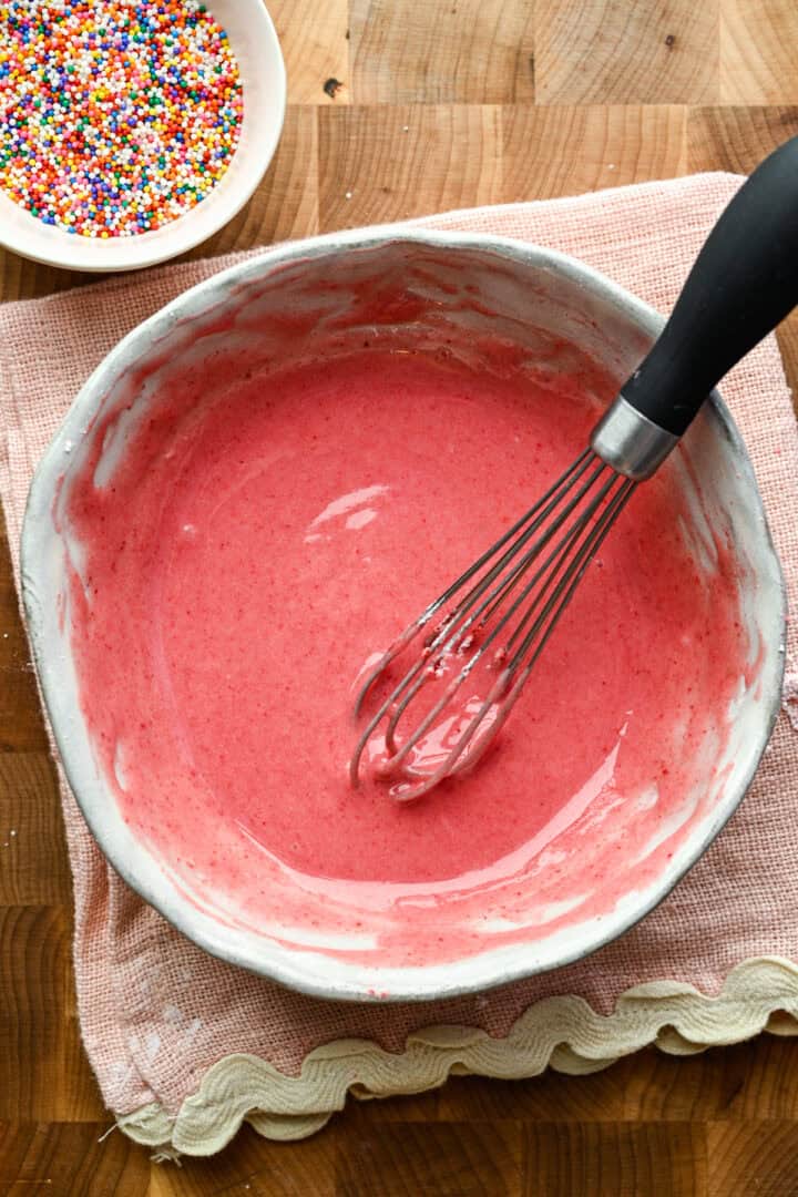 Overhead view of strawberry frosting in a bowl.