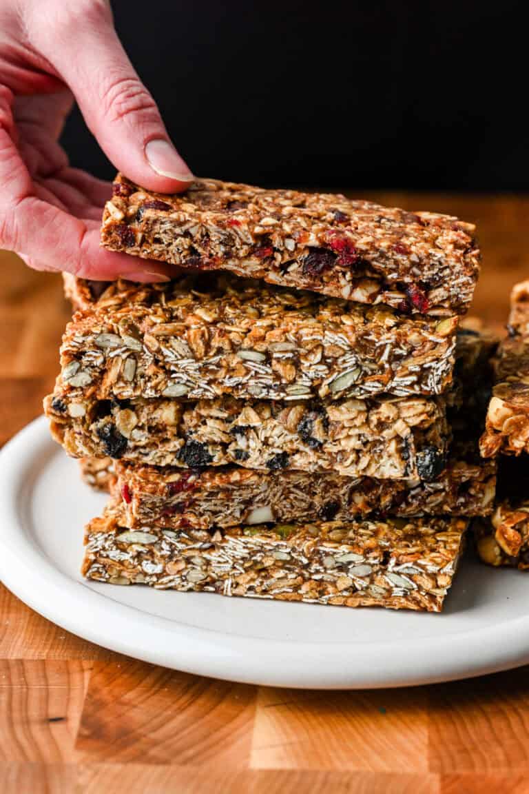 A stack of homemade granola bars with a hand reaching in to grab the one on top.