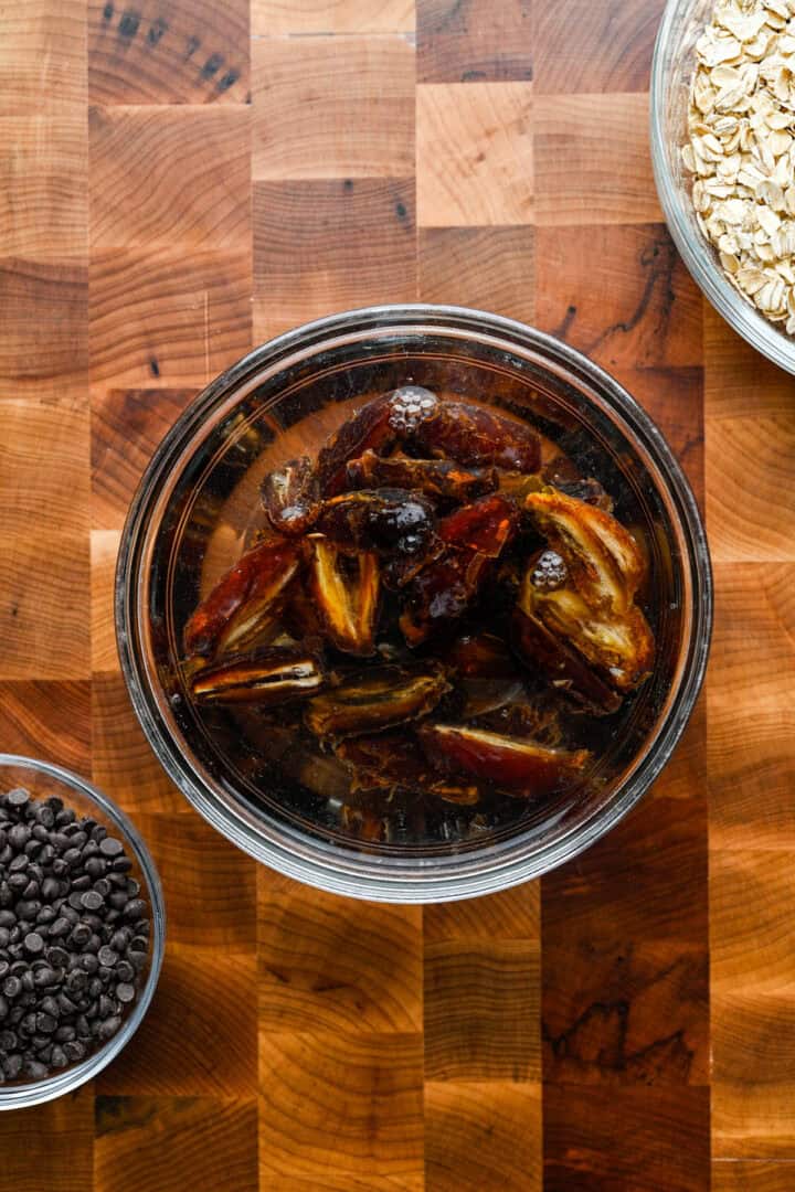 Halved medjool dates soaking in a bowl of water.