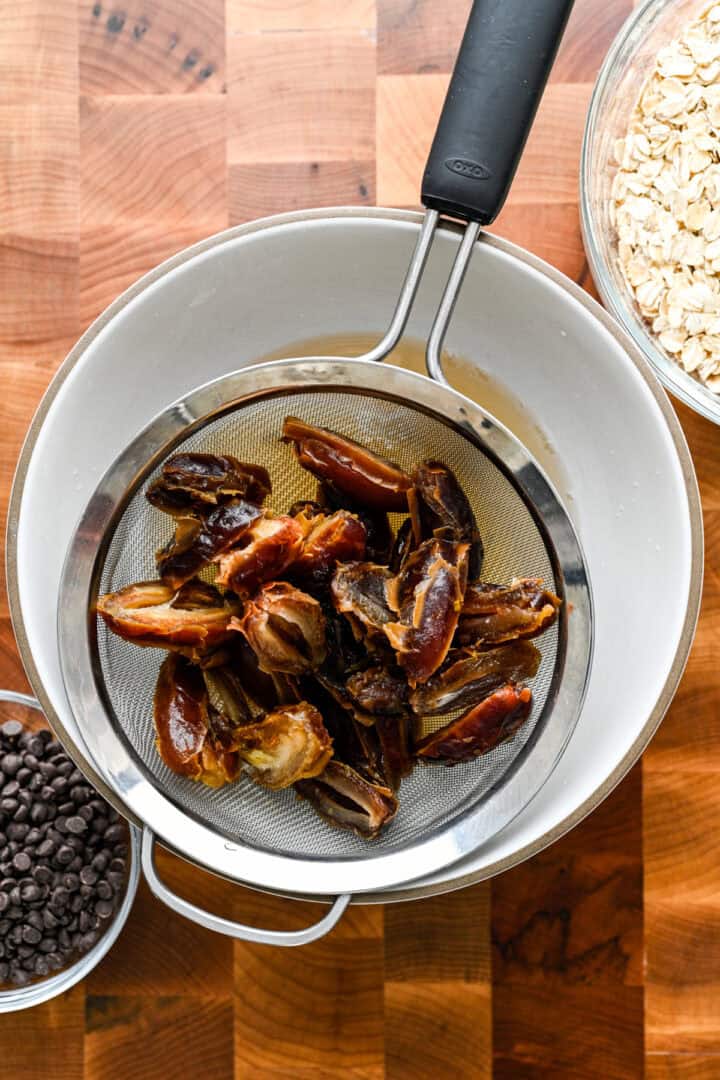 Dates in a strainer above a bowl.