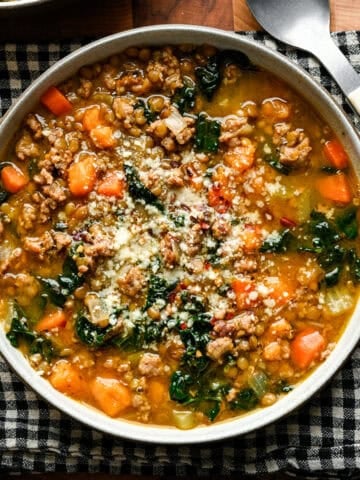 Overhead view of sausage kale lentil soup in a bowl with some parmesan on top.