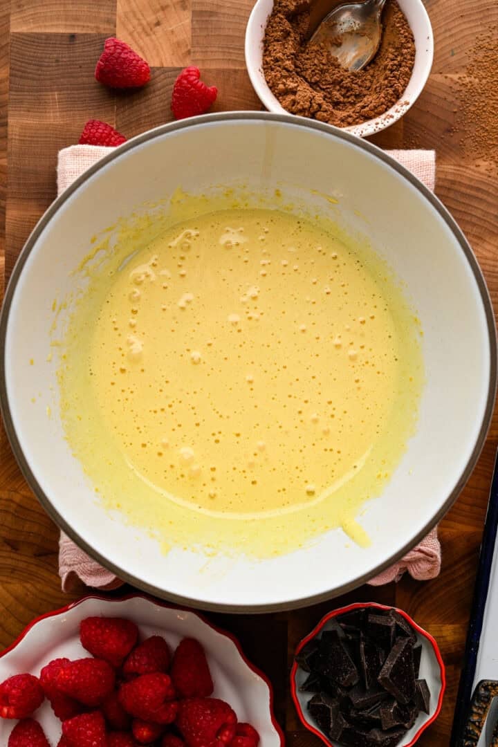 Eggs and sugar whipped together in a white bowl.