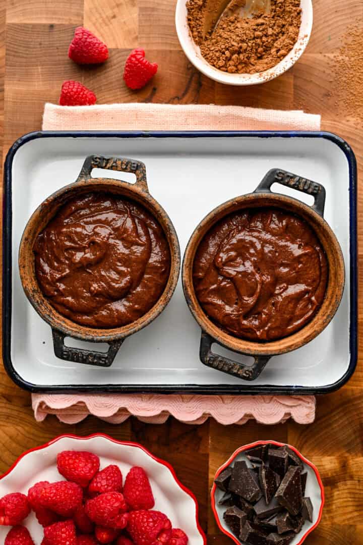 2 cast iron ramekins filled with chocolate lava cake batter.