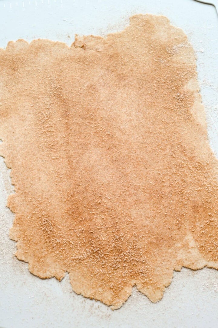 Dough rolled out into a thin sheet and sprinkled with cinnamon sugar.