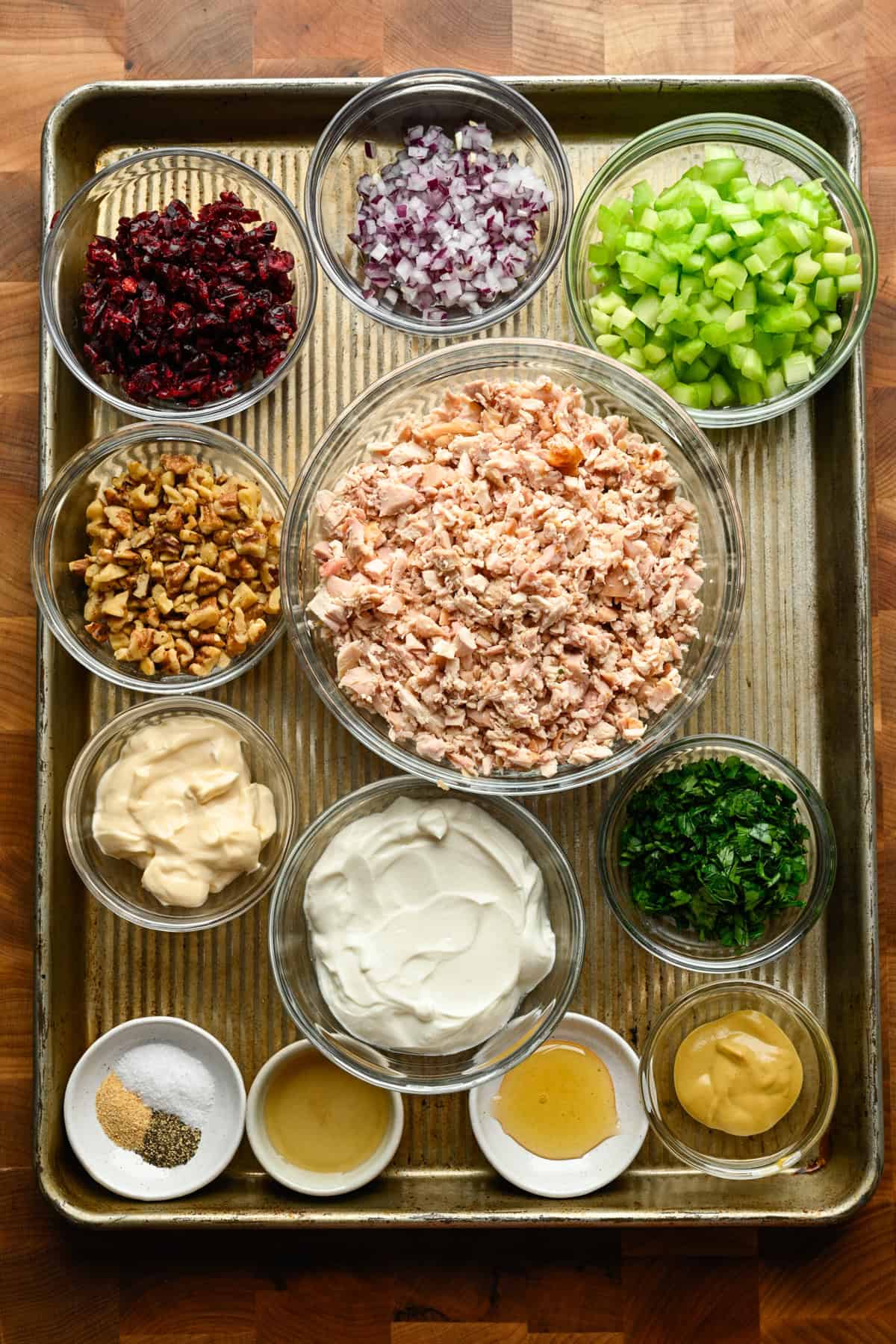 Overhead view of ingredients for cranberry walnut chicken salad on a sheet pan.