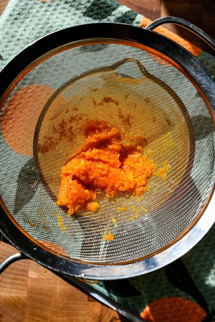 Orange zest in a strainer after being strained out.