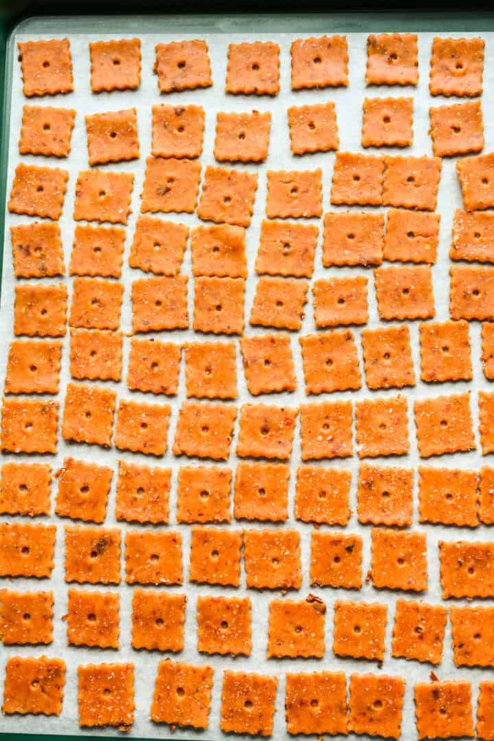 Cheez its squares laid out on parchment before baking.