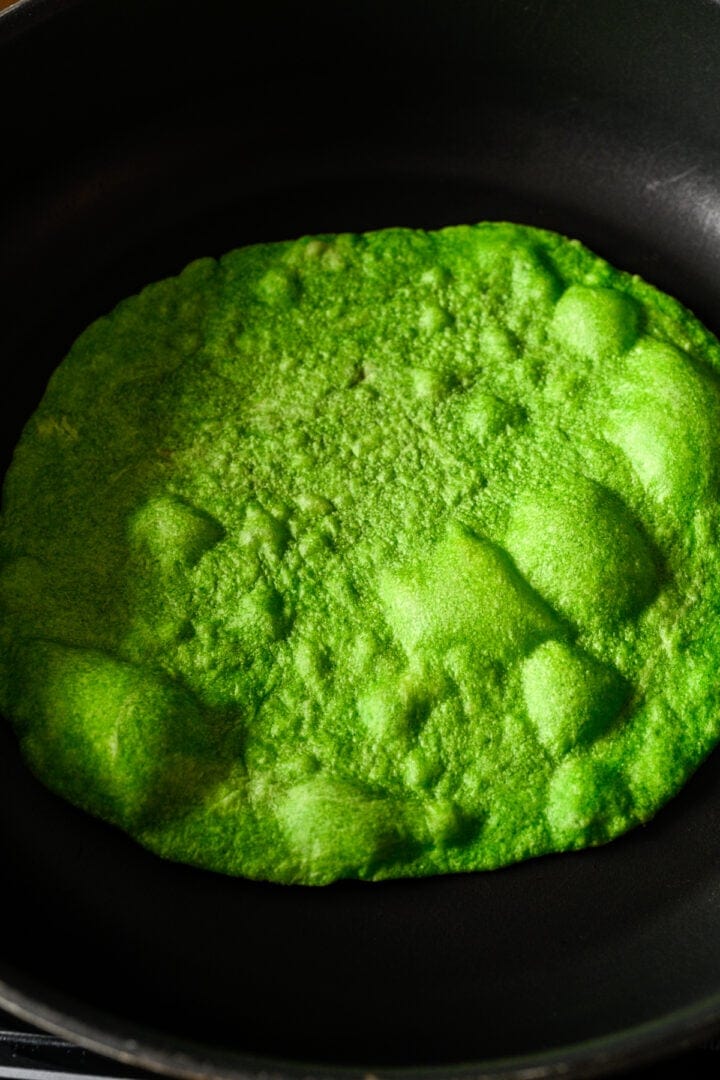 Overhead view of spinach tortilla cooking in a pan.