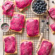 overhead view of homemade blueberry pop tarts with bright pink icing and sprinkles on a cooling rack.