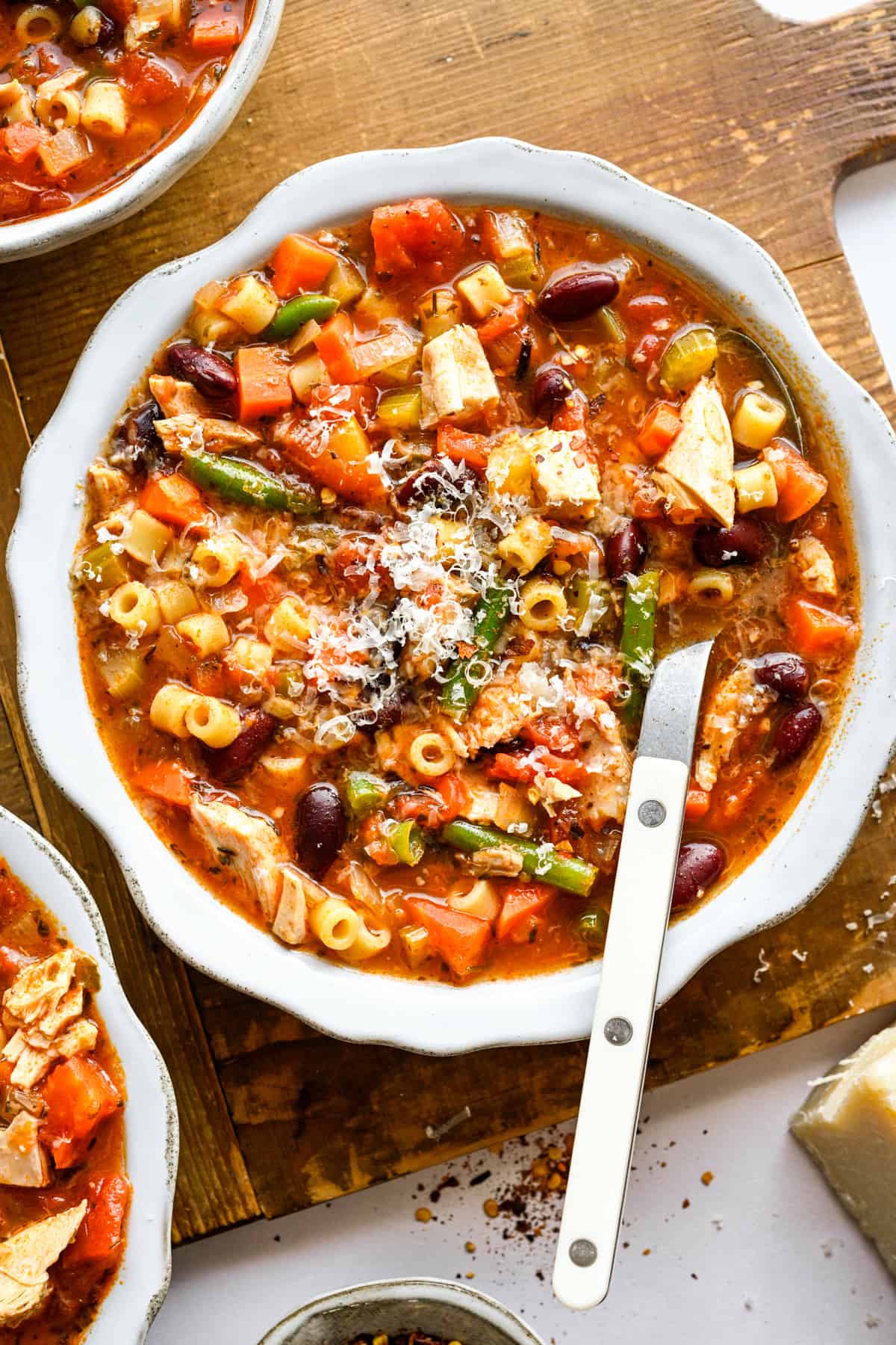 Chicken Minestrone Soup garnished with grated parmesan cheese in a white bowl.