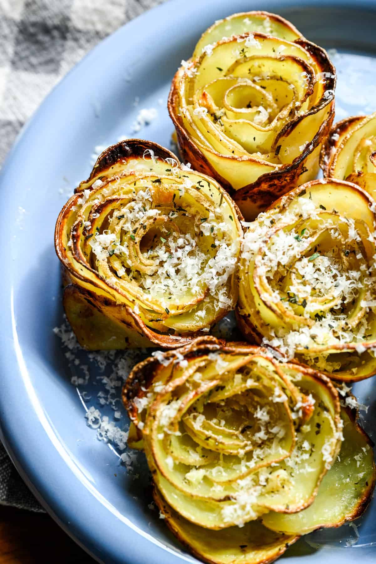 Overhead view of potato roses on a plate covered in parmesan.