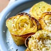 Overhead view of potato roses on a plate covered in parmesan.