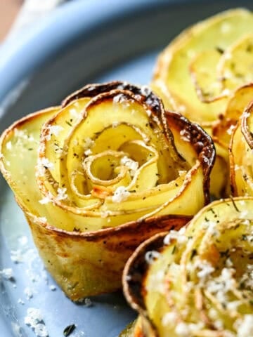 Overhead view of potato roses on a plate covered in parmesan.