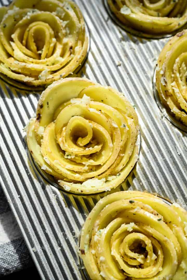 Overhead view of potato rose in a muffin tin slot before baking.