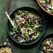 Kale broccoli salad in a green bowl with a fork.