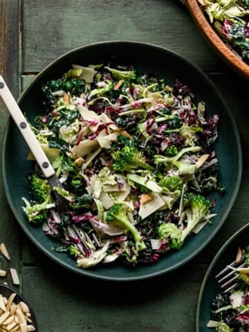 Kale broccoli salad in a green bowl with a fork.