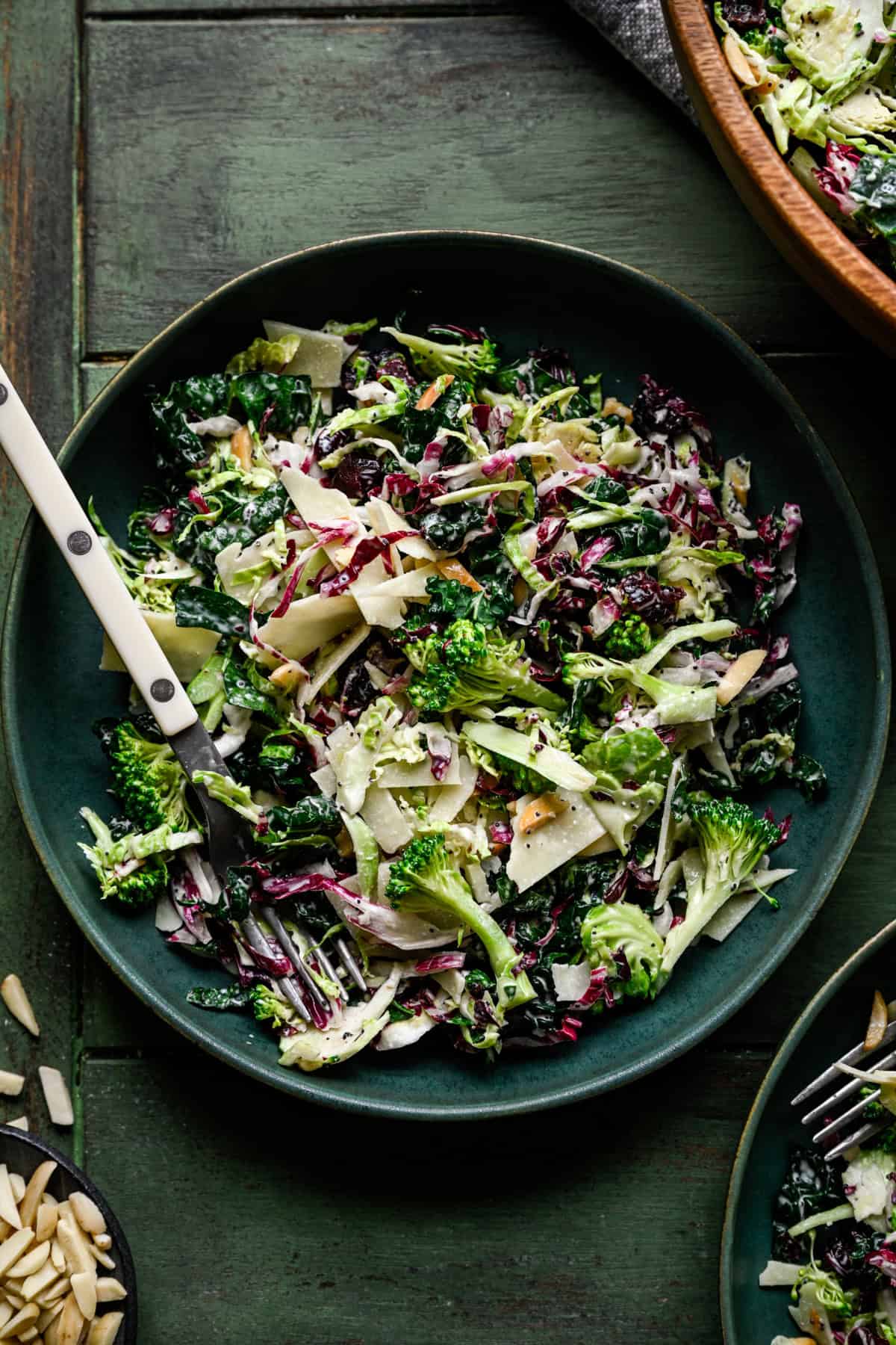 Kale broccoli salad in a green bowl with a fork.
