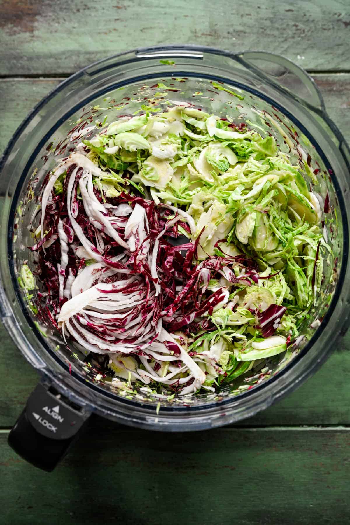 Brussels sprouts, radicchio, and broccoli stems sliced in a food processor.
