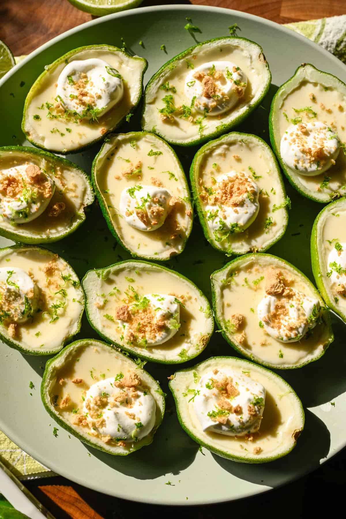 Overhead view of lime possets topped with whipped cream and graham cracker crumbs on light green plate.