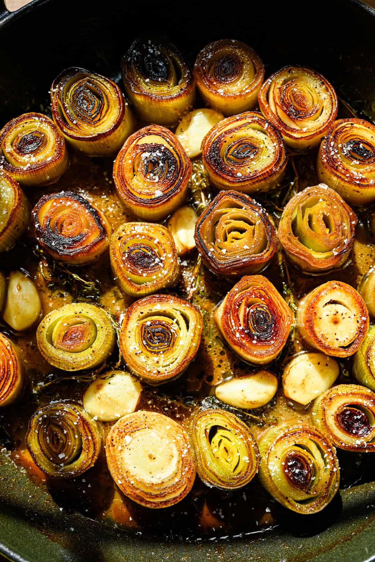 Overhead view of cooked leeks in a pan.