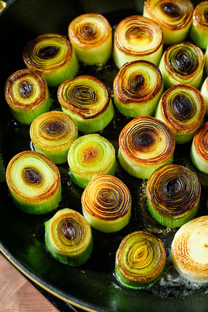 Overhead view of cooked leeks in a pan.