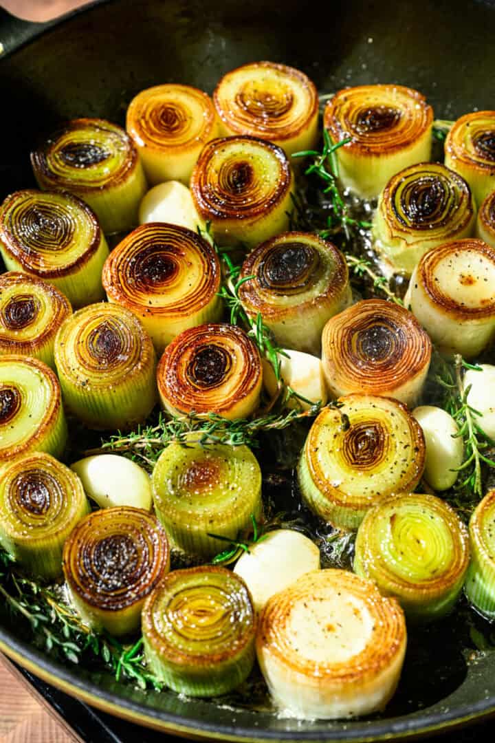 Overhead view of cooked leeks in a pan.