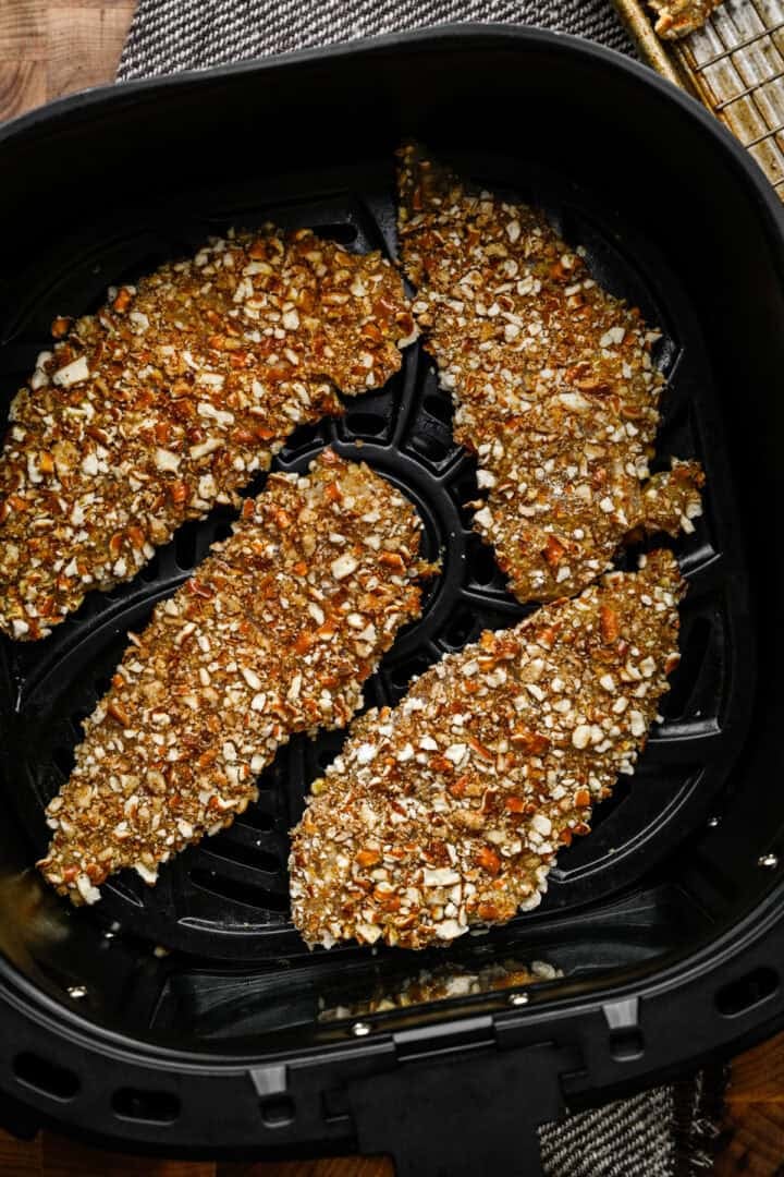 Chicken tenders in an air fryer before being cooked.